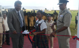 Minister of Public Security, Khemraj Ramjattan (left), Commissioner of Police, Seelall Persaud (right) and Sade Jones, a student of the Green Acres Primary School during the cutting of the ribbon.
