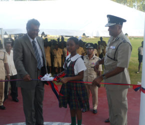 Minister of Public Security, Khemraj Ramjattan (left), Commissioner of Police, Seelall Persaud (right) and Sade Jones, a student of the Green Acres Primary School during the cutting of the ribbon. 