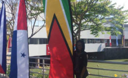 Abbigale standing pruoudly beside a Guyana flag located outside a university in Peru.
