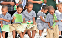 Caria Caria children examine the exercise books with wildlife photos on the cover, which they received during President David Granger’s visit to that community yesterday. (Ministry of the Presidency photo)
