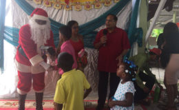 Prime Minister Moses Nagamootoo and his wife Sita Nagamootoo with few of the children as Santa Claus shares toys
