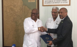 Finance Minister Winston Jordan (left) shaking hands with CEO of the Caribbean Development Fund Rodinald Soomer after signing the agreement as Minister of Agriculture Noel Holder looks on. 