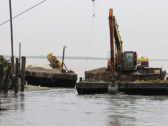 An excavator mounted on a pontoon works to desilt the Cowan Street outfall (Ministry of Public Infrastructure Photo) 