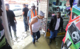 Mayor Patricia Chase-Green (second from right) and Town Clerk Royston King (right) checking the depth of flooding in the Full Range store on Regent Street today.