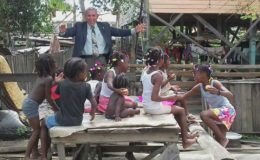 Minister of Public Health, Dr George Norton interacting with children in Angoy’s Avenue after his visit with the parents of Lonette Nicholson-Prince, the hairdresser at the NA Psychiatric Hospital who was stabbed to death by her estranged husband on Wednesday. (Photo by Bebi Oosman)