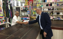 Minister Dominic Gaskin (right) shaking hands with the proprietor of Phagoo and Sons yesterday. 