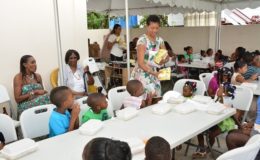 Daniele Harmon-Klein distributes presents at the Christmas party as her grand mother, Ms. Susan Clement (seated second from left) looks on. (Ministry of the Presidency photo)

