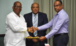 Minister of Finance, Winston Jordan (left) and President of the Guyana Gold and Diamond Miners’ Association, Terrence Adams shake hands after signing two agreements. Also in photo is Minister of Natural Resources, Raphael Trotman.  (GINA photo)