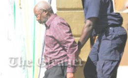 Moravian Minister Rupert Clarke (left) is escorted from the St Elizabeth Parish court by a policeman. 