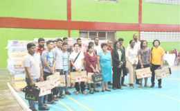 Some of the beneficiaries of the donations of laptops, mattresses and stationery, standing with Minister of Social Protection Amna Ally (fifth, right front row), Minister of Public Telecommunications Catherine Hughes (fourth, right front row) and Minister within the Ministry of Education Nicolette Henry (third, right front row).