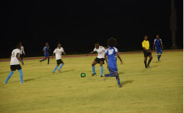 Rondel Hutson (center) of Den Amstel in the process of receiving a pass in the midfield third while being pursed by Dwayne St. Kitts (no.10) of Pouderoyen during their team’s match-up in the Petra Organization/Limacol Football Championship at the National Track and Field Centre, Leonora. 