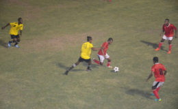 Leonardo Adams (red) trying to maintain control of the ball while being challenged by Cleon Forester (yellow) of Western Tigers while other teammates look during their group match in the 2nd Annual Petra Organization/Limacol Football Championship at the GFC ground.