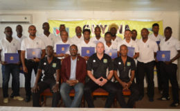 Newly certified-Successful coaches at the CONACAF D-License and Goalkeeping Course pose with their certificates in the presence of [sitting from left to right] GFF Technical Development Officer Lyndon France, GFF President Wayne Forde and GFF Technical Director Ian Greenwood.