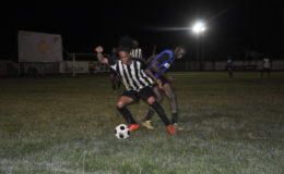 Job Caesar (left) of Santos trying to maintain possession of the ball while under pressure from a Uitvlugt marker during their quarterfinal contest in the Stag Nation Cup at the Tucville Ground