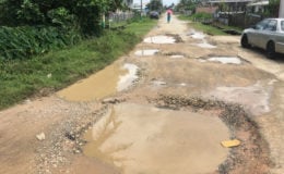 One end of the road that is decorated with large potholes, which are filled with water after little rainfall.