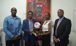 FIFA Director Véron Mosengo-Omba (2nd from left) exchanges tokens with Hon. Minister Nicolette Henry (2nd from right) in the presence of GFF President Wayne Forde (right) and First Vice President Ret. Brigadier Bruce Lovell