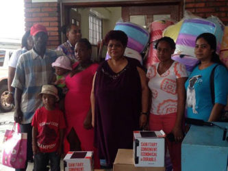 Minister of Social Protection Amna Ally (at center) surrounded by the fire victims who received relief packages yesterday. The families of Mark James (left) and Simone Morrise (second from right) lost their Princes Street homes on Wednesday. Rosemarie Abrams (right) was one of the victims from last Friday’s fire at Kitty, during which three houses were destroyed.