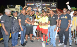 Captain of Showstoppers Hubert Pedro (centre) collects the championship trophy and prize money from Guinness representative Robeson Brotherson in the presence of teammates and Banks DIH Limited members following the final of the Guinness ‘Greatest of the Streets’ West Demerara/East Bank Demerara Zone Championship at the Pouderoyen Tarmac. (Orlando Charles photo)