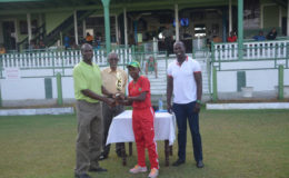 Shemaine Campbelle collects her player of the match trophy from former West Indies fast bowler Reon King while national selector Rayon Griffith, looks on.
