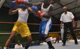Deshon Elcock (left in red) evades a right hand from Suriname’s Tony Lemin while landing a right of his own. (Orlando Charles photos)