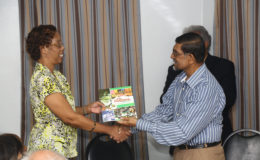 Editor of the Guyana Annual Petamber Persaud (right) presenting a copy of the latest publication to a representative of the National Library. (Photo by Keno George)