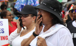  Two of the women involved in the “funeral procession” feign tears. 
