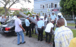 Police officers, assisted by public-spirited citizens, removing a utility pole that broke and fell on a car on Brickdam yesterday, after it was hit by a minibus. (Photo by Keno George)