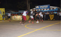 Bent Street’s Joshua Browne (right) races down the right side while being pursued by an Albouystown player in the National Gymnasium in the Petra Organization/GT Beer Futsal Championships Saturday.