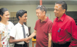 Math teacher Bernard Assing, congratulates student Aaron Mohammed, who earned a distinction in the CSEC math exam. Also in photo are Mohammed’s parents Nazir, right, and Nadia