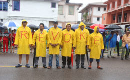 Rain men: Movement Against Parking Meter supporters donned raincoats yesterday to protect themselves against the natural elements. The coats also doubled as canvasses to spell out the group’s call for a revocation of the metered parking project. (Photo by Keno George)