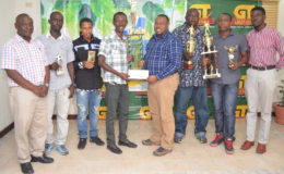 Petra Organization Co-Director Troy Mendonca (4th from right) handing over the championship trophy and winner’s cheque to Western Tigers head-coach Calvin Allen while representatives of the other competing teams as well as Banks DIH Communication Officer Troy Peters (left) share in the moment. (Orlando Charles photo)