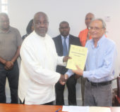 Chairman of the Commission of Inquiry into the Education System Ed Caesar (left) submits the preliminary report to Minister of Education Rupert Roopnaraine, while the other members of the commission look on. (Photo by Keno George)