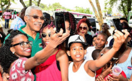 Youngsters taking selfies with President David Granger in the National Park yesterday (Ministry of the Presidency photo)