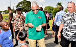 The smallest kite! President David Granger examines a tiny kite presented to him by a little boy during his walk through the National Park. (Ministry of the Presidency photo)