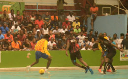 Jermaine Adams (left) of Back Circle bracing for the impending tackle from Bent Street’s Okeene Fraser (center) in their semifinal showdown in the Petra Organization Futsal Championship at the National Gymnasium