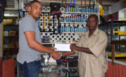 Proprietor of Jude’s Bike Shop, Jude Bentley (left) hands over their sponsorship to representative of the Boyce & Jefford Committee, Claude Bennett on Monday at the Robb Street location of the business place.