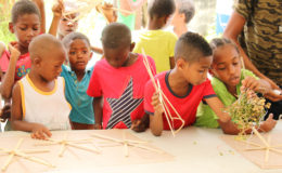 Albouystown children making their own kites yesterday with materials donated by the Ambitious Future Leaders Youth Club, of the same community. Members of the organisation assisted in attaching paper to some 200 kite frames using bottled glue and Clammy cherry (gamma cherry) at the Bel Air Green, Bel Air Street, Albouystown. (Photo by Keno George)  