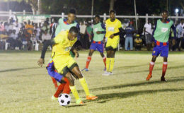 Nicholas McArthur (yellow) of Chase Academy battling to maintain possession of the ball against a Sir Leon Lessons player during their semi-final affair at the Ministry of Education ground in the Milo Secondary School Football Championships. (Orlando Charles photo)