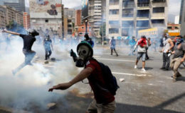 A demonstrator throws a tear gas canister back to policemen during an opposition rally in Caracas, Venezuela April 6, 2017. REUTERS/Carlos Garcia Rawlins 