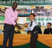 Twelve-year-old Fenny Adrian receiving his certificate from Senior Education and Training Officer at the Office of the Presidential Advisor on Youth Empowerment Ronald Austin.