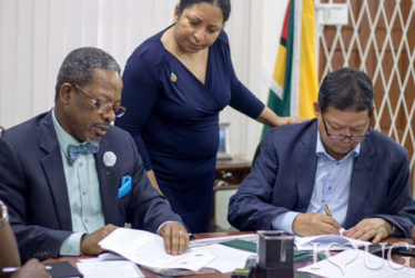 University of Guyana Vice Chancellor Professor Ivelaw Griffith (left) signing two memoranda with MovieTowne Chief Executive Officer Derek Chin for solar energy production and student housing. Looking on is Dr Paloma Mohamed, Deputy Vice Chancellor of Philanthropy, Alumni and Civic Engagement