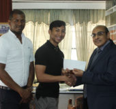  President of the GOA, Kalam Juman-Yassin hands over the GOA sponsored travel ticket to Miguel Wong in the company of GTTA president Godfrey Munroe (Royston Alkins photo)