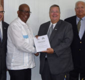 Mission Director of USAID, Christopher Cushing (second from right) handing over the signed document to Minister of Finance, Winston Jordan in the presence of General Development Office Director Ted Lawrence (at right) and Principal Officer, Mark Oviatt
