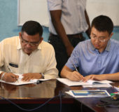 Brian Tiwari (at left), of BK International, signs an agreement for the supply of stone with CHEC Project Manager Keliang Liu at the CJIA yesterday. (Keno George photo)