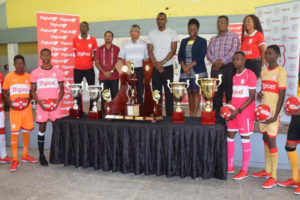 Members of the launch party for the 7th annual Digicel Schools Football Championship pose with the respective top four trophies at the West Demerara Secondary School. Standing atop the stage include Sherwin Osbourne (left), Dr. Wazir Mohamed (2nd from left), Director of Sport Christopher Jones (4th from left), GFF third  Vice-President Thandi McAllister (3rd from right) and Digicel Head of Marketing Jacqueline James (right).