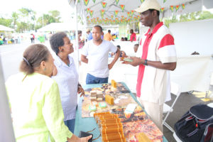 Curious customers interacting with one of the exhibitors at D’Urban Park (Keno George Photo)