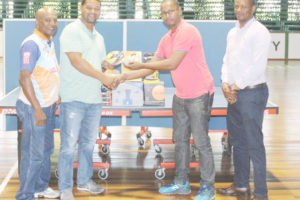 Proprietor of Dominion House, Dwayne Monroe second right hands over his contribution to President of BTTSC Timothy Cornelius on Friday. Also in the photo, Godfrey Munroe (right) and Linden Johnson. (Royston Alkins photo)