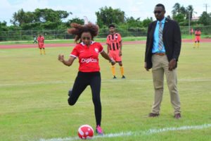 Digicel Head of Marketing Jacqueline James (centre) does the ceremonial kickoff to start the seventh annual Digicel Schools Football tournament at the National Track and Field Centre, Leonora in the presence of Director of Sport Christopher Jones. (Orlando Charles photo)