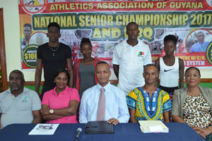 AAG President Aubrey Hutson, sitting (centre) with other AAG officials, along with athletes (standing) at yesterday’s launch (Orlando Charles photo)