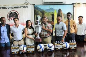 Top Brandz Director of Marketing and Sales, Pratima Prashnajeet, (left) hands over the winners’ trophy to Director of Petra, Troy Mendonca  in the presence of Guyana Football Federation’s president Wayne Forde, extreme left and GFA’s vice president Arron  Fraser (third right).
